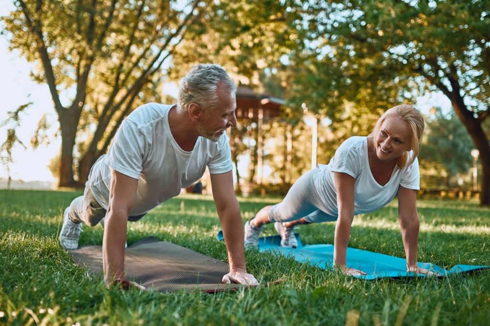 A couple doing yoga in a park.